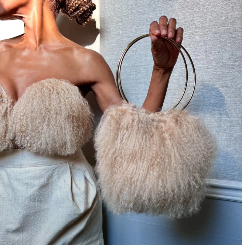 A cream textured statement bag with sculptural ring handles